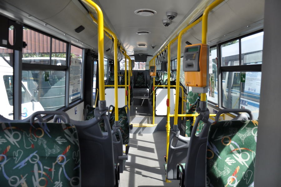 Przestrzeń pasażerska autobusu miejskiego, widoczny kasownik biletów