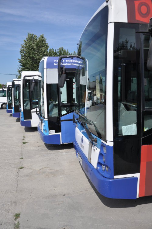 Prezentacja biało-niebieskich autobusów Solaris, pięć autobusów stojących obok siebie. Widoczny lewy bok pojazdów.