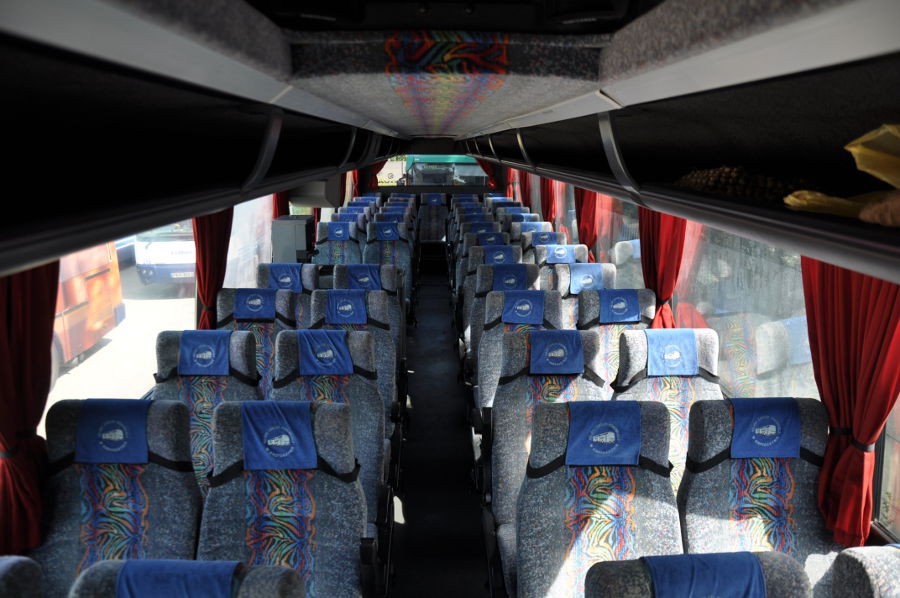 Przestrzeń pasażerska autokaru, widoczne fotele oraz czerwone zasłonki.