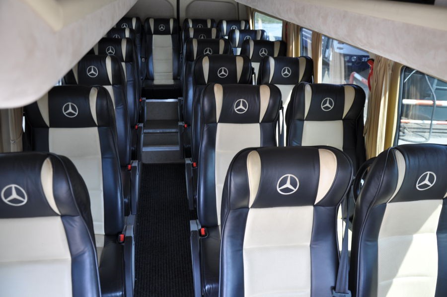 Prezentacja busa Mercedes - przestrzeń pasażerska, widoczne skórzane fotele z logo Mercedesa.